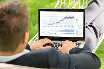 Stock Broker Lying In Hammock Using Laptop