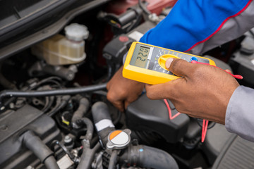 Fototapeta premium Mechanic Checking Battery With Multimeter