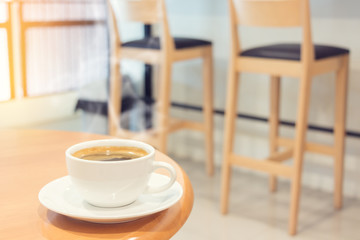 White cup of coffee on brown wood table in cafe.