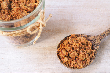 A spoon of brown sugar on a wooden background.