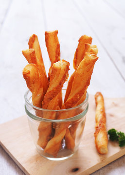 Bread sticks in a glass jar on a wooden table.