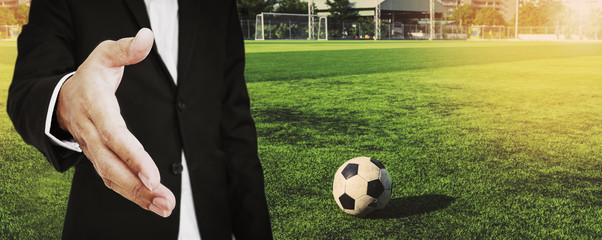 A man in suit extending hand to handshake with soccer ball at soccer field  © SasinParaksa