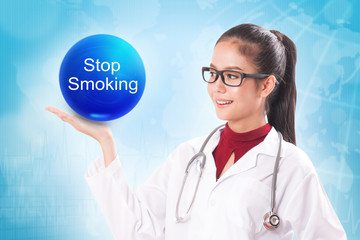 Female doctor holding blue crystal ball with stop smoking sign on medical background.