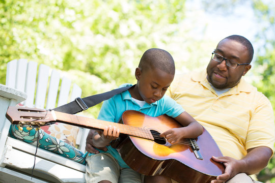 African American Man Teaching His Son How To Play The Guitar