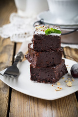 Chocolate brownies with powdered sugar and cherries on a dark wooden background. Selective focus.