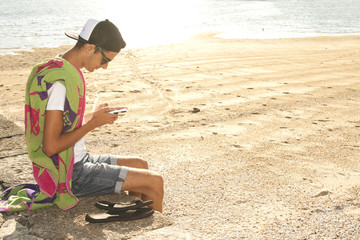 Fototapeta na wymiar boy with the phone on the beach