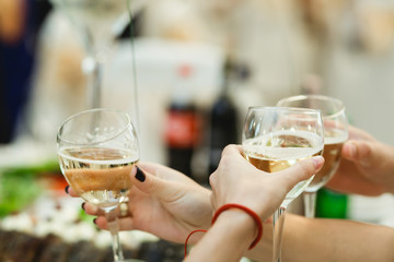 People cheers with glasses full of white wine