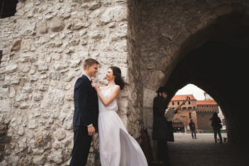 Gorgeous wedding couple, bride, groom kissing and hugging near wall