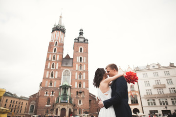 Elegant beautiful wedding couple walking on the main square in Krakow