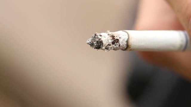 smoldering cigarette in the hand closeup