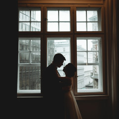 Silhouettes of newlyweds standing in the front of a bright windo