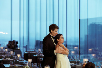 Groom holds bride's shoulders tender standing with her in an emp