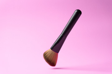 Makeup brush falling on the floor with color background
