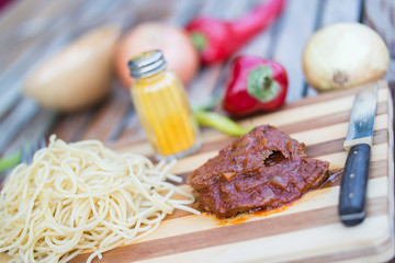 Beef with tomato sauce, sphagetti and vegetables.