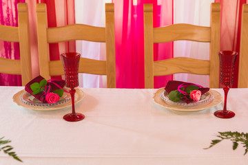 Spring table set decoration with flowers. White plates, red wineglasses