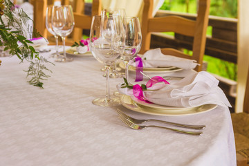 Wedding summer table decoration with flowers. White plates, forks, knifes and wineglasses