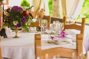 Wedding summer table decoration with flowers. White plates, forks, knifes and wineglasses