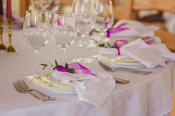 Wedding summer table decoration with flowers. White plates, forks, knifes and wineglasses