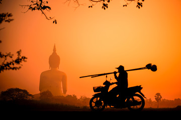 Obraz na płótnie Canvas Silhouette Buddha and a worker on motorbike