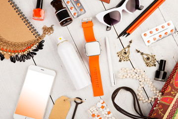 smart watch, smart phone, straw bag, notepad, sunglasses, key, pills, cosmetics makeup and essentials on white wooden desk
