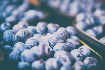 Fresh blueberry in plastic box at market, local food healthy background in vintage hipster style