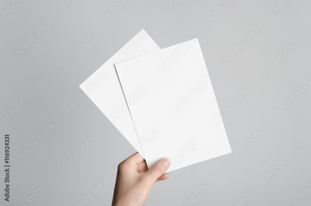 Sticker A5 Flyer / Invitation Mock-Up - Male hands holding blank flyers on a gray background.