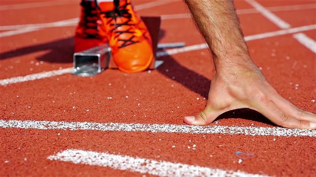 Single track and field sprinter in a stadium starting out of the block, slow motion