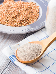 Buckwheat grain and flour on wooden table. Vertical image. Closeup