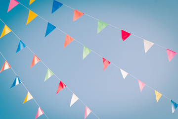 Colorful bunting flags on blue sky with retro filter effect