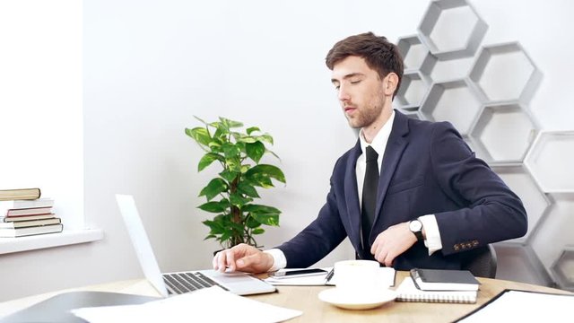 Young successful businessman working at laptop in office. Slow motion.