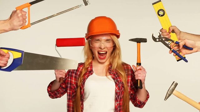 Cheerful girl builder and hands around her with building tools in them on a white background