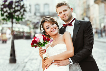 Bride and bridegroom holding bouquet and smiling
