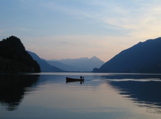 Dusk shot of lone fishing boat on Brienzersee lake, Switzerland with Niesen mountain in far distance