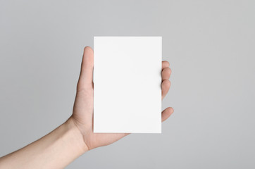Obraz premium A6 Flyer / Postcard / Invitation Mock-Up - Male hands holding a blank flyer on a gray background.