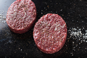 Meat for burgers, grilling, barbecue, bbq. Fresh, spicy, uncooked, delicious beef for hamburgers on dark background with copy space closeup
