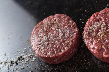 Meat for burgers, grilling, barbecue, bbq. Fresh, spicy, uncooked, delicious beef for hamburgers on dark background with copy space closeup
