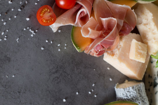 Jambon mix. Ham. Traditional Italian and Spanish salting, smoking, dry-cured dish - jamon Serrano and prosciutto crudo sliced with melon on grey background. Copy space. Closeup. 