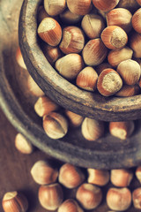 Hazelnuts in rustic round clay bowl on wooden background
