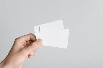 Business Card Mock-Up (85x55mm) - Male hands holding blank cards on a gray background.