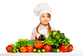 Young cook in uniform with fresh vegetables