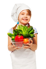 Smiling girl holding bowl full of fresh vegetables