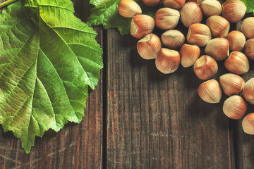 Hazelnuts and leaves on wooden background. Top view with copy space