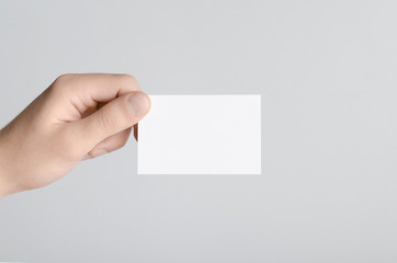 Fototapeta premium Business Card Mock-Up (85x55mm) - Male hands holding a blank card on a gray background.