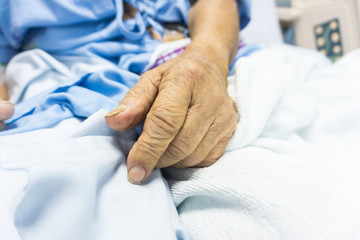 Obraz na płótnie Canvas Close up of old man hand lying on the hospital bed