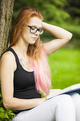 Obraz premium young red haired woman student relaxing learning in park sunny weather