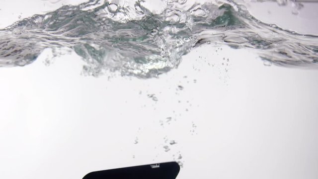Smart phone with incoming call on display falling in water with splash on white background slow motion closeup