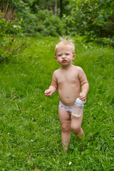 Маленький ребенок в трусах ходит босиком по траве