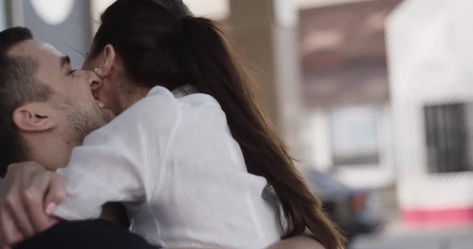 Happy couple embracing in love romantic and fun. Charming brunette woman running to hug her boyfriend at urban street. They start turning around swirling and laughing