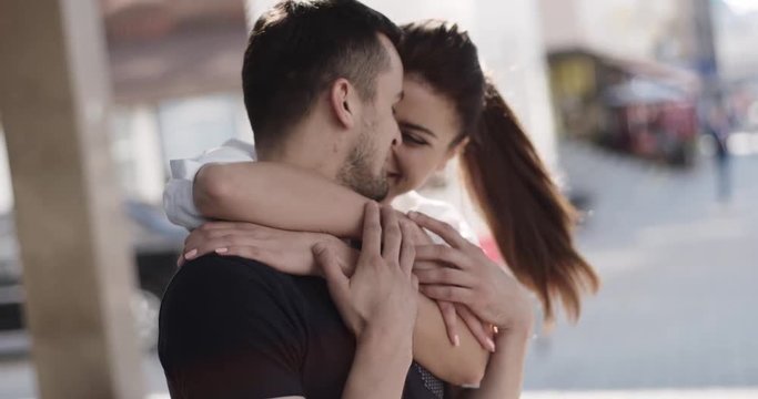 Happy couple hugging in the city. Beautiful brunette woman running to hug and jumping on boyfriend's back