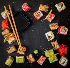 Traditional Japanese food - sushi, rolls and sauce on a black background. Top view